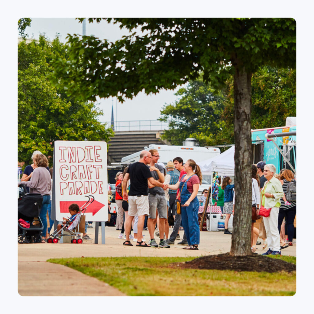Event attendees shaking hands and greeting each other at the Indie Craft Parade